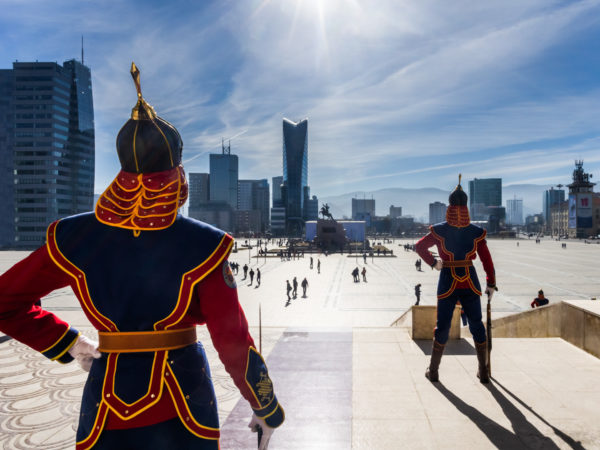 Soldats mongols en tenue d'apparat postés devant le bâtiment du Parlement. Vus de dos. Au fond, des immeubles et gratte-ciels. Ulan Bator - Mongolie - 2013. © Grégory Dziedzic Photography