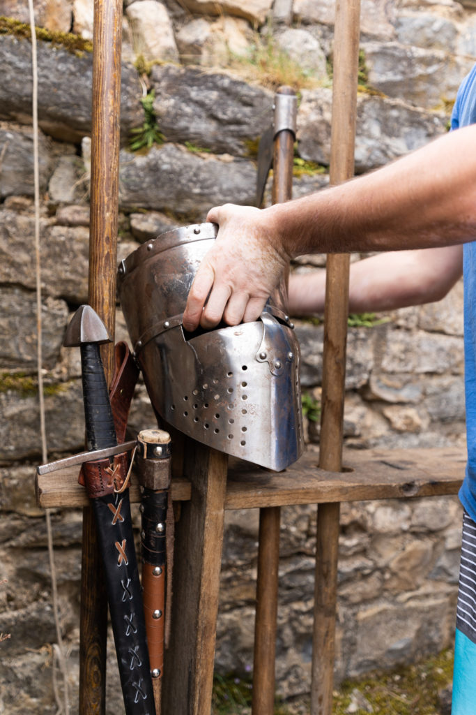 Un membre de la compagnie médiévale "Les Faydits d'Oc" se saisit d'un heaume métallique en amont de la représentation au château de Peyrelade. Rivière-sur-Tarn, août 2020.