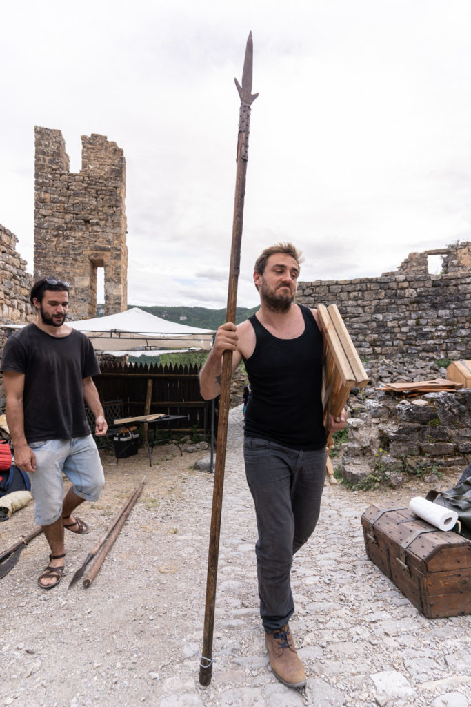 Un membre de la compagnie médiévale "Les Faydits d'Oc" porte une lance en amont de leur représentation au château de Peyrelade. Rivière-sur-Tarn, août 2020.