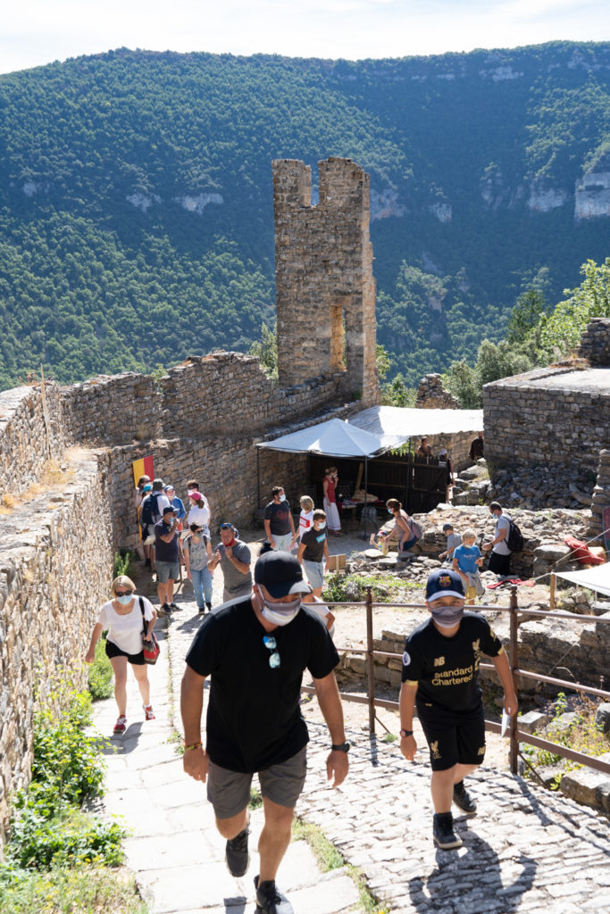 Des touristes arrivent dans le château de Peyrelade et commencent à en gravir les marches.  Ils portent des masques en raison de la situation sanitaire liée au Covid-19. Rivière-sur-Tarn, août 2020.