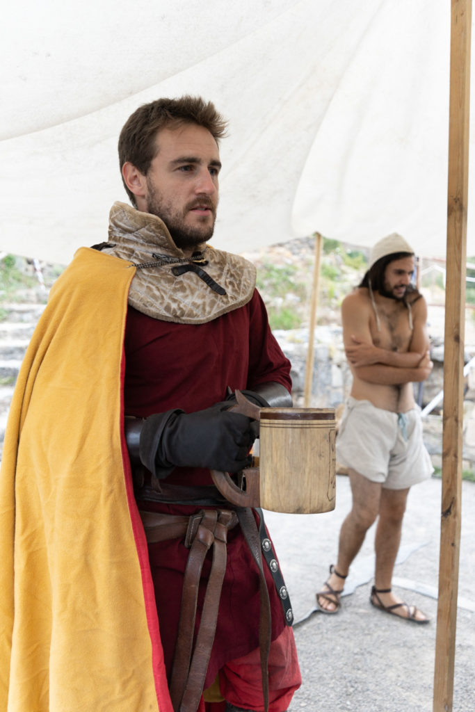 Messire Sylvain, de la compagnie médiévale "Les Faydits d'Oc" boit une bonne chope de bière alors que le troubadour Bohémond frissonne et songe à se vêtir plus chaudement la veille d'une représentation au chiateau de Peyrelade. Rivière-sur-Tarn, août 2020.