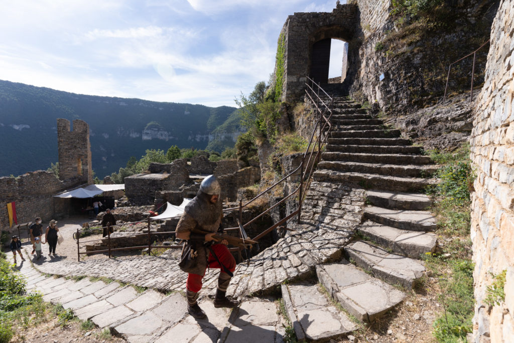 Un arbaletrier joué par un membre de la compagnie médiévale "Les Faydits d'Oc" gravit les marches du château de Peyrelade pour rejoindre son poste. Rivière-sur-Tarn, août 2020.