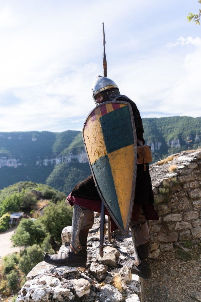 Un soldat portant lance et bouclier joué par un membre de la compagnie médiévale "Les Faydits d'Oc" fait la vigie sur les murailles du château de Peyrelade. Rivière-sur-Tarn, août 2020.