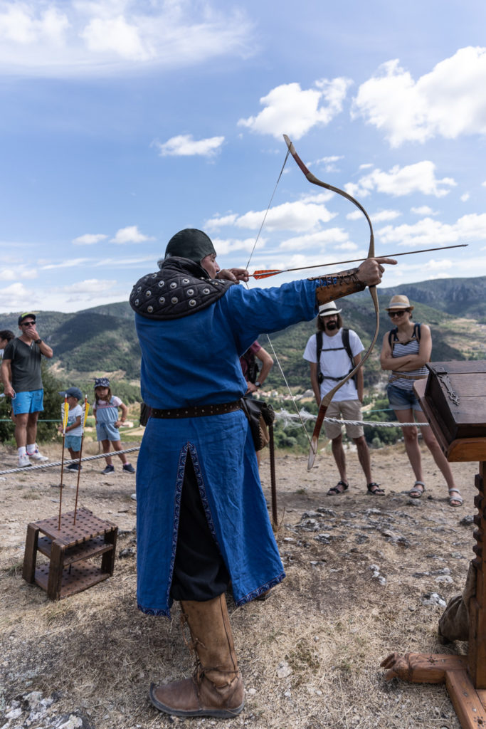 Messire Roger, de la compagnie médiévale "Les Faydits d'Oc", fait une démonstration de tir à l'arc devant des visiteurs du château de Peyrelade. Rivière-sur-Tarn, août 2020.