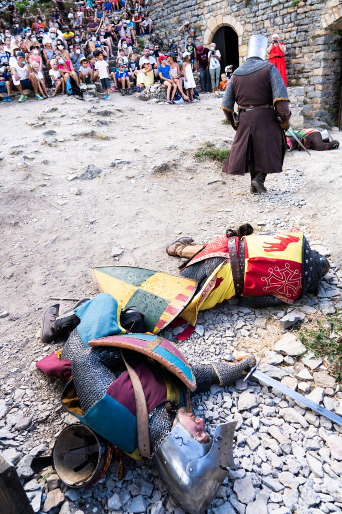 Sire Yvan, de la compagnie médiévale "Les Faydits d'Oc", s'éloigne de ses victimes après un combat pendant une représentation devant un parterre de spectateurs au château de Peyrelades. Les touristes portent un masque en raison de la situation sanitaire liée au Covid-19. Rivière-sur-Tarn, août 2020.