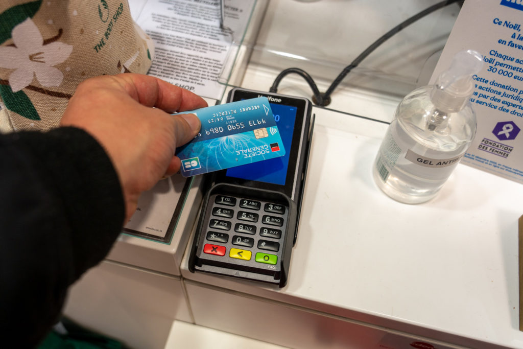 Un consommateur règle ses courses de Noel par carte bleue, une bouteille de gel hydroalcoolique posée à côté du terminal de paiement. Toulouse, le 21 décembre 2020.