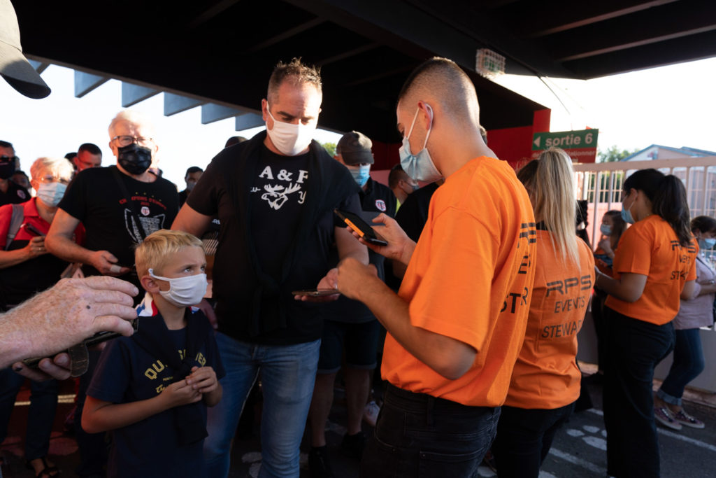 Un employé d'accueil vérifie les passes sanitaires d'un membre du public.  Près de 19000 contrôles de pass sanitaire ont été effectués dimanche soir au stade Ernest Wallon à l’occasion de la rencontre entre le Stade Toulousain et le Rugby Club Toulonnais, qui s’est jouée à guichet fermé. Après une année de matches à huis-clos en raison de la crise sanitaire, le public s’est rendu en masse au stade à l’occasion du match de clôture de la 2e journée du Top 14, que le Stade Toulousain a remporté 41 à 10. Toulouse, stade Ernest Wallon, le 12 septembre 2021.