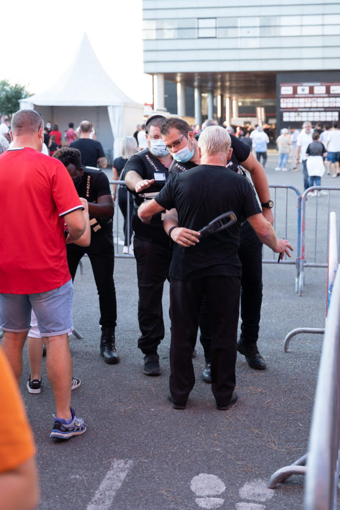 Un agent de sécurité passe un membre du public au détecteur de métaux (la "raquette"). Après une année de matches à huis-clos en raison de la crise sanitaire, le public a pu de nouveau se rendre au stade Ernest Wallon à l’occasion du match de clôture de la 2e journée du Top 14. Champion de France en titre, le Stade Toulousain recevait le Rugby Club Toulonnais. Le match s'est joué à guichets fermés et près de 19000 contrôles de pass sanitaires ont été effectués à l'entrée du stade. Le Stade Toulousain l’a remporté par 41 à 10. Toulouse, stade Ernest Wallon, le 12 septembre 2021.