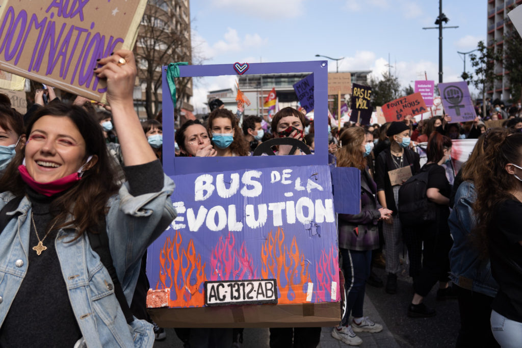 Des manifestantes marchent derrière une pancarte à fenêtre sur laquelle on peut lire "Le bus de la révolution" lors de la manifestation pour la journée sur les droits des femmes. Toulouse, 8 mars 2021.