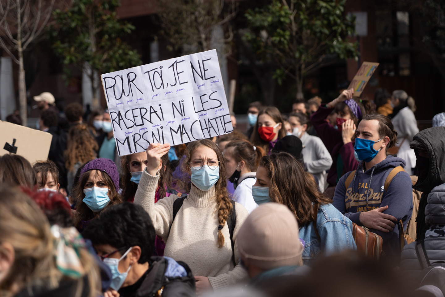 Une manifestante montre une pancarte sur laquelle on peut lire "Pour toi, je ne raserai ni les murs, ni ma chatte" lors de la manifestation pour la journée sur les droits des femmes. Toulouse, 8 mars 2021.