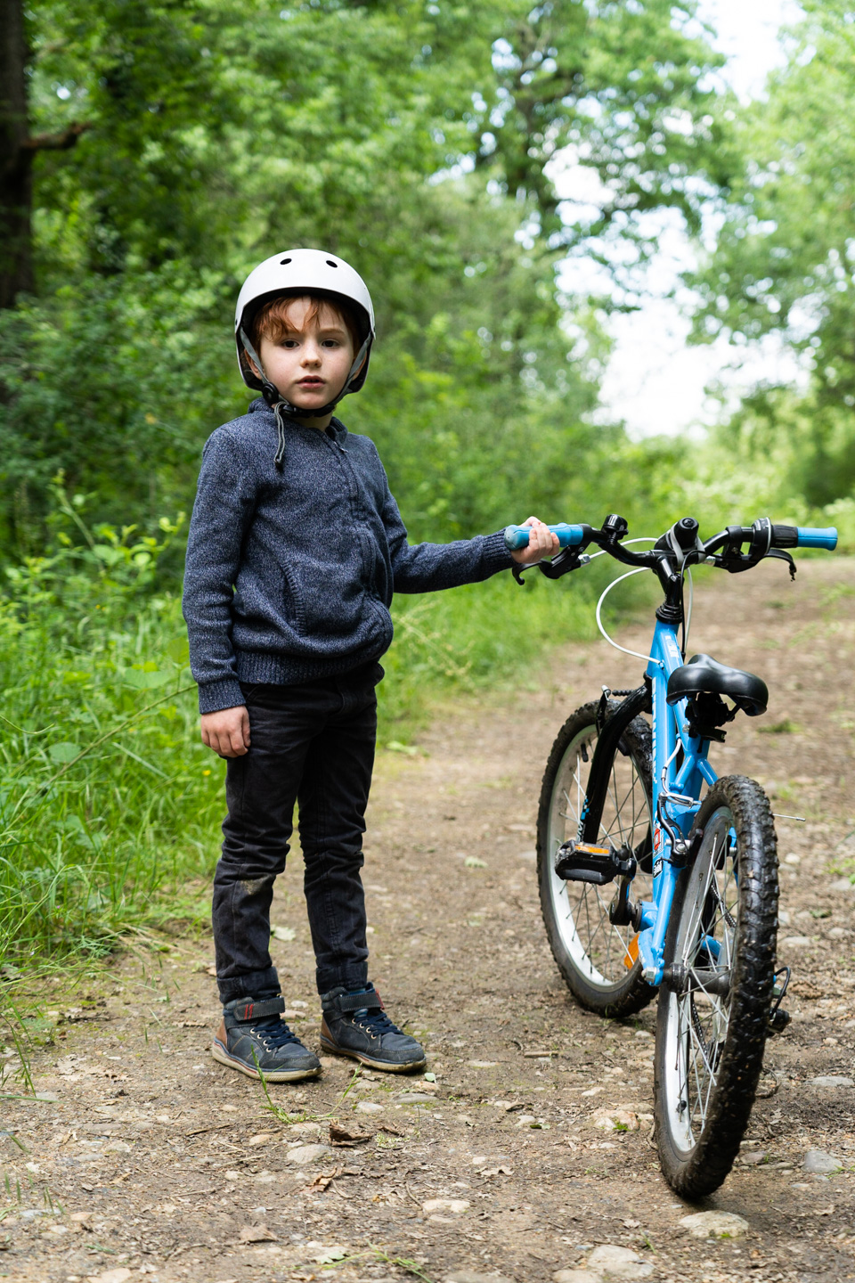 Un enfant pose à côté de son vélo sur un chemin de terre dans la forêt de Bouconne, à proximité de Toulouse, à l'issue du déconfinement. Toulouse - France - mai 2020.