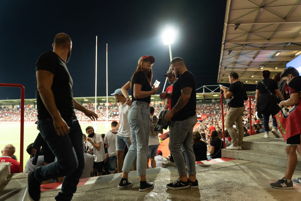 Des spectateurs viennent d'arriver dans le stade et s'apprêtent à rejoindre leur place dans les gradins. Après une année de matches à huis-clos en raison de la crise sanitaire, le public a pu de nouveau se rendre au stade Ernest Wallon à l’occasion du match de clôture de la 2e journée du Top 14. Champion de France en titre, le Stade Toulousain recevait le Rugby Club Toulonnais. Le match s'est joué à guichets fermés et près de 19000 contrôles de pass sanitaires ont été effectués à l'entrée du stade. Le Stade Toulousain l’a remporté par 41 à 10. Toulouse, stade Ernest Wallon, le 12 septembre 2021.