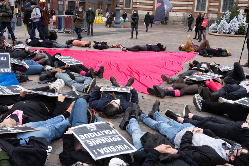 Des militants d'Act Up s'allongent sur le sol pour un "die in" autour du triangle rose étendu sur les pavés de la place du Capitole à l'occasion du rassemblement organisé par ActUp Sud-Ouest pour la journée mondiale contre le VIH/SIDA. Ils dénoncent notamment la politique sanitaire du gouvernement pendant la crise du Covid. Toulouse, le 1er décembre 2020.