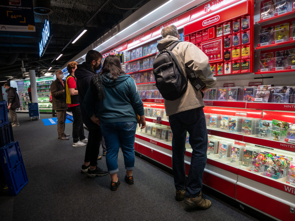 Des consommateurs regardent le rayon jeux vidéos d'une grande enseigne pendant les courses de Noël. Toulouse, le 21 décembre 2020.