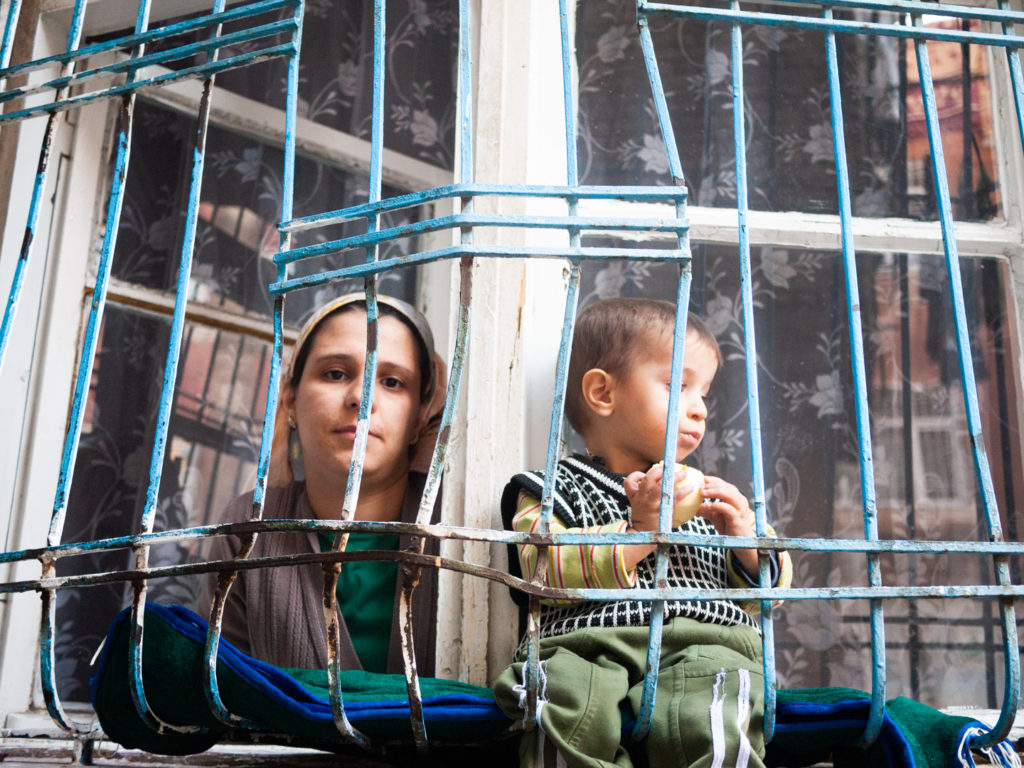 Une jeune femme kurde et son enfant regardent les passants depuis la fenêtre fermée de barreaux de leur domicile. Diyarbakir (Turquie), novembre 2010.