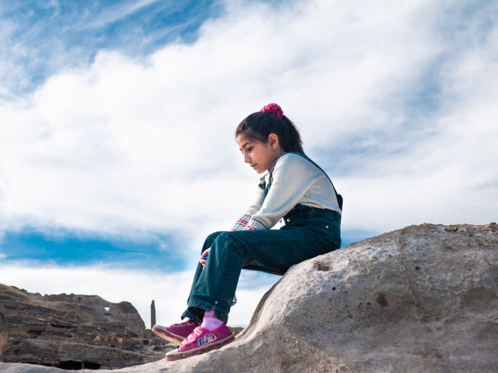 Une petite fille assise sur un promontoir rocheux. Hasankeyf (Turquie), novembre 2010.