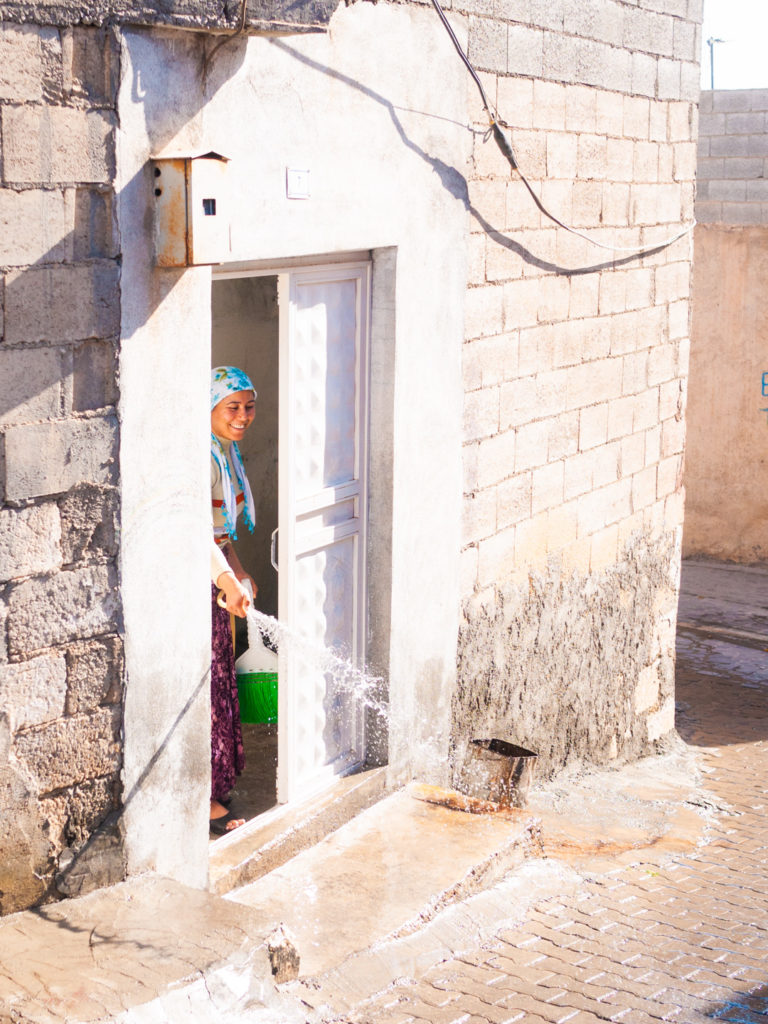 Une jeune femme en train de faire le ménage arrose le pas de la porte de son domicile. Urfa (Turquie), novembre 2010.